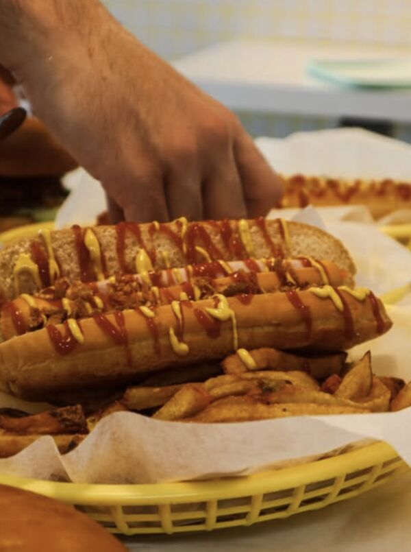 Hot-dogs ketchup moutarde et frites dans un panier jaune